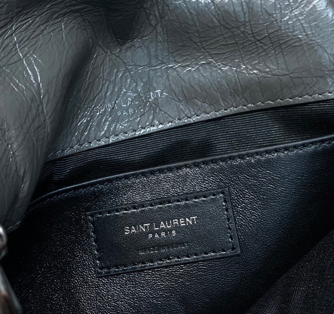 Black leather bag with interior brand label patch reading “SAINT LAURENT PARIS”