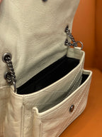 Cream leather bag interior with black lining, opening flap, and chain hardware.