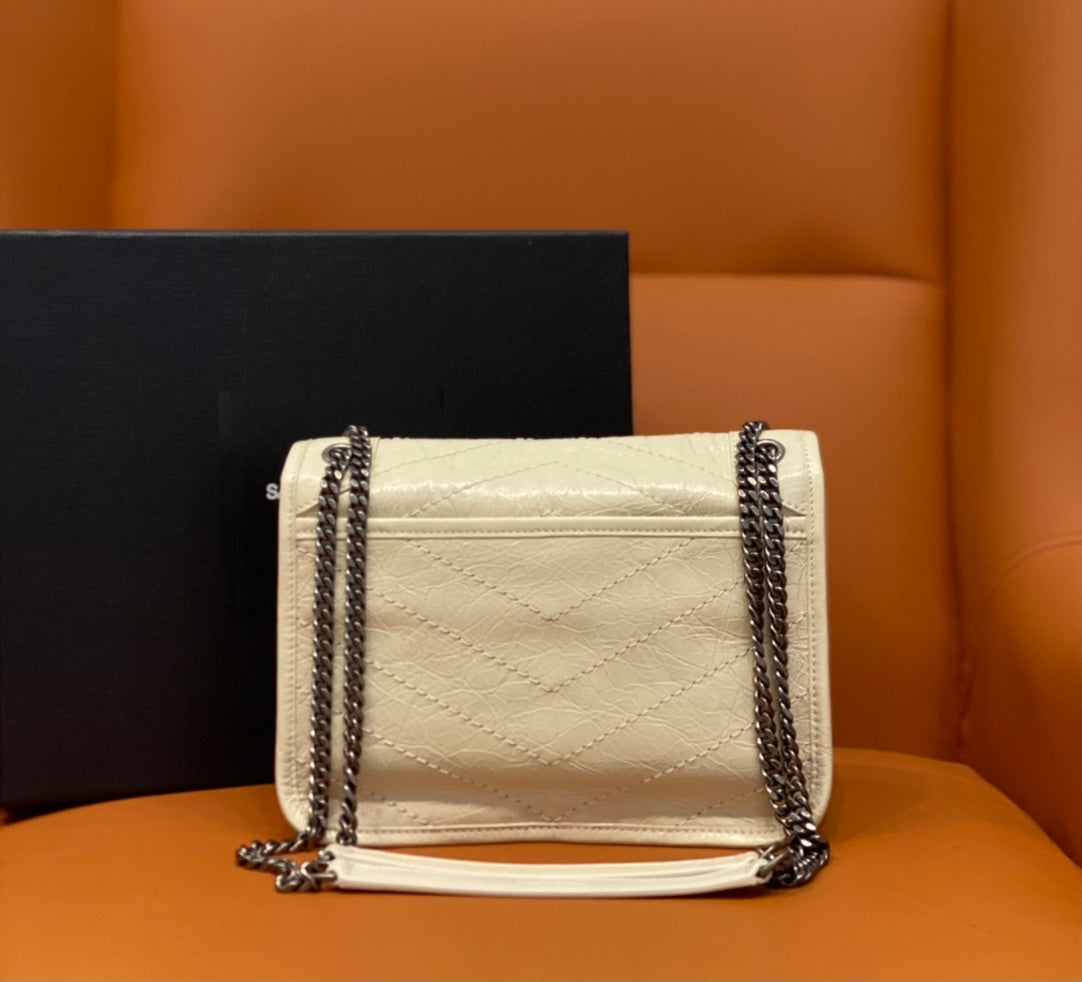 Cream quilted crossbody bag with flap closure and silver chain straps.