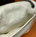 Cream quilted leather bag with silver chain hardware at top corner.
