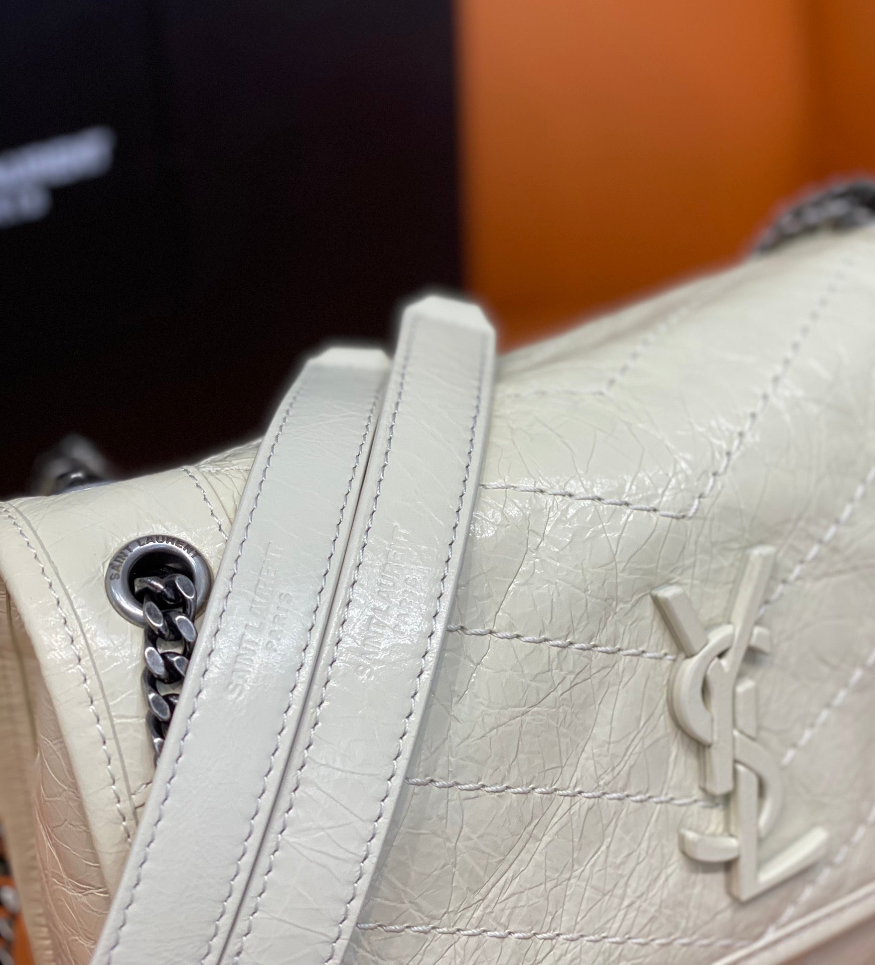 Cream leather shoulder bag side view with chain strap and YSL-style monogram.