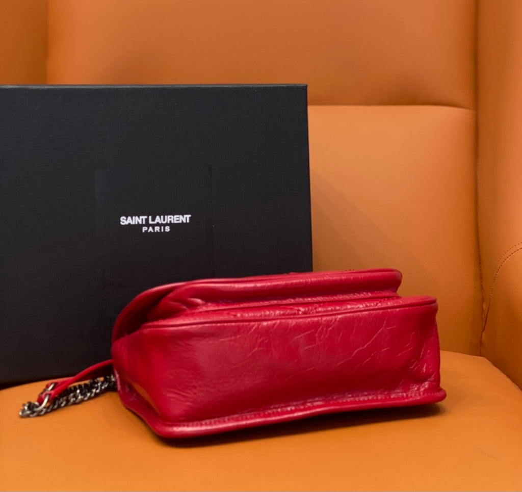 Red shoulder bag with chain strap and rounded flap, side view