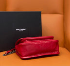Red shoulder bag with chain strap and rounded flap, side view