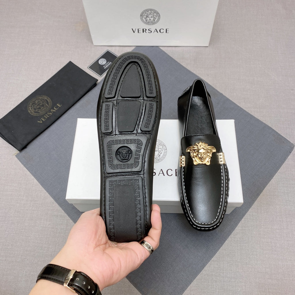 Versace black leather loafers showing outsole and gold lion medallion on the vamp