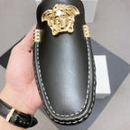 Versace black leather loafer with close-up gold lion emblem and contrast white stitched detailing