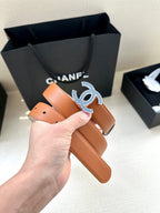 Orange leather belt held up with large blue-and-silver logo buckle