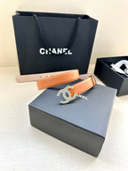 Tan leather belt with large logo buckle and adjustable hole rows