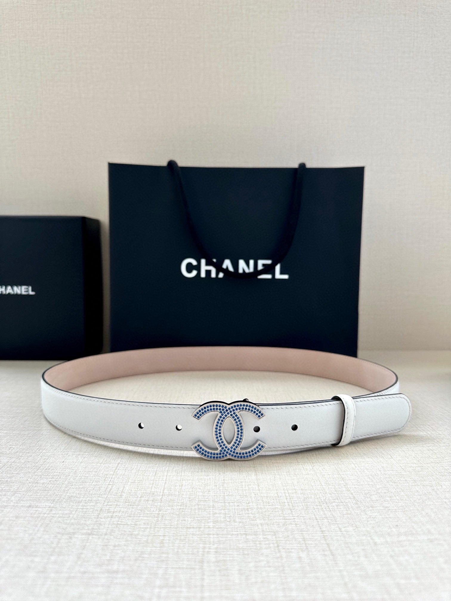 Chanel belt featuring white leather strap with blue crystal CC buckle centerpiece