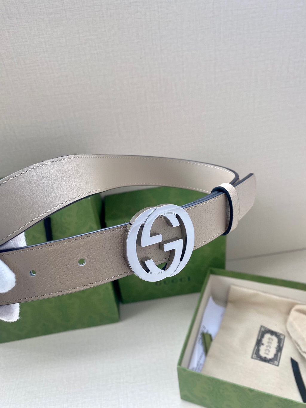 Gucci belt close-up: light beige leather strap with silver circular GG buckle