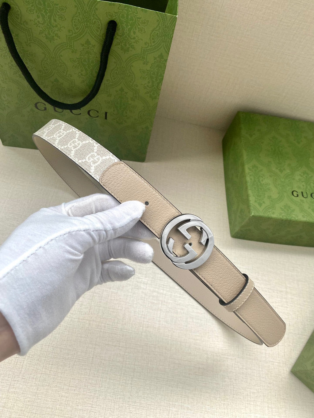 Gucci belt with light beige leather strap and silver circular GG buckle close-up