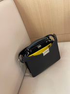 Black crossbody bag with yellow interior pocket and metal zipper hardware