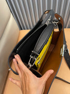 Open black crossbody bag showing yellow lining pocket and interior zipper detail