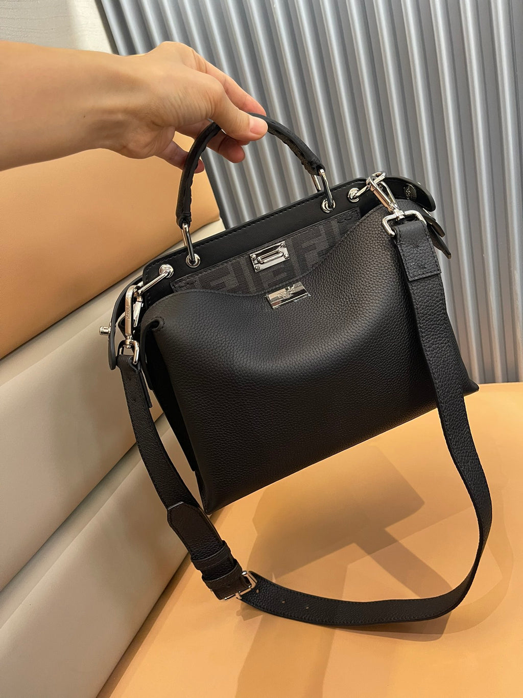Black leather satchel with top handle, front logo plaque, and shoulder strap