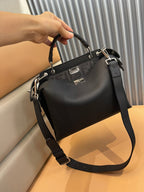 Black leather satchel with top handle, front logo plaque, and shoulder strap