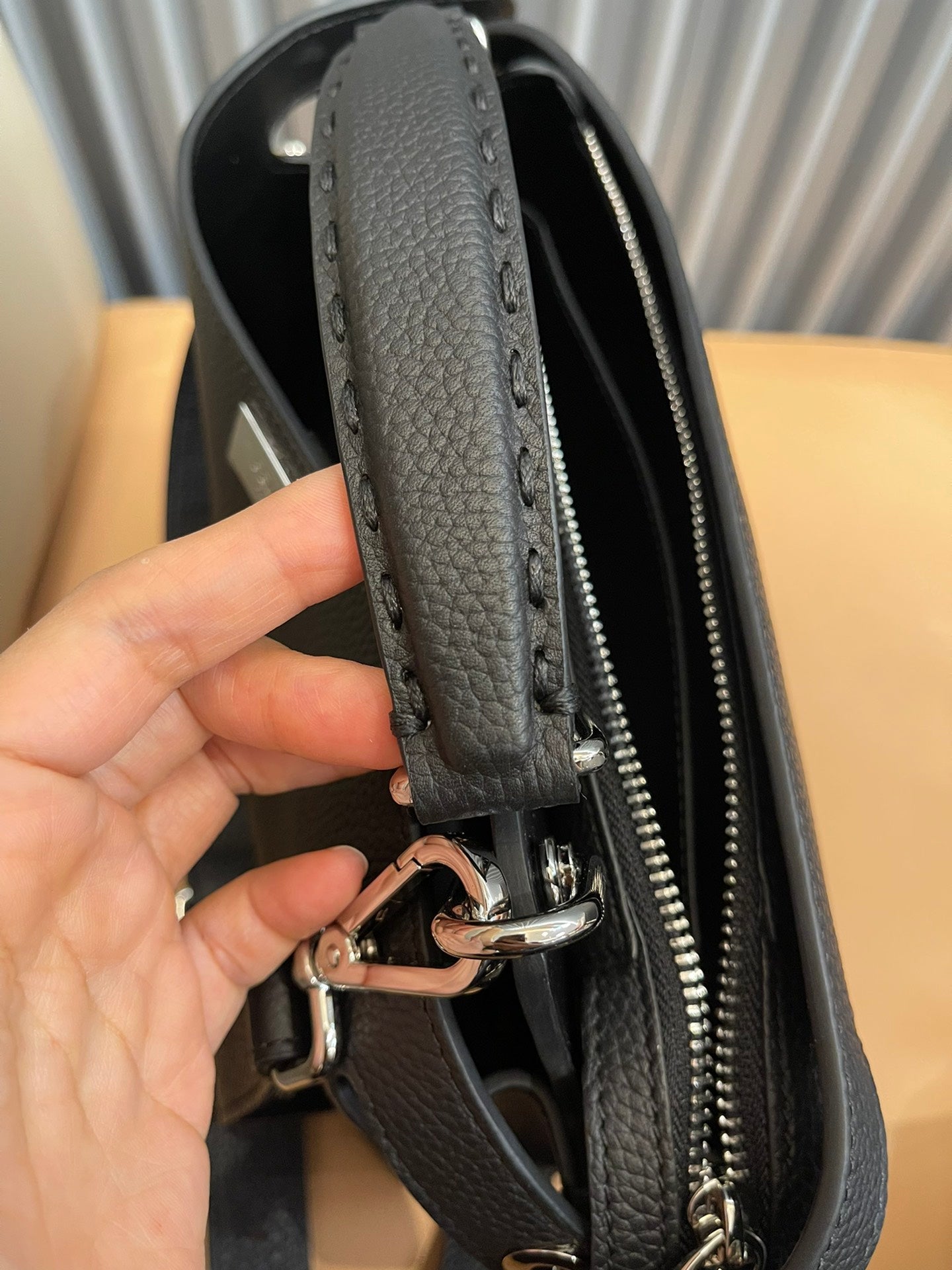 Black leather bag edge with zipper track and reinforced strap attachment clip