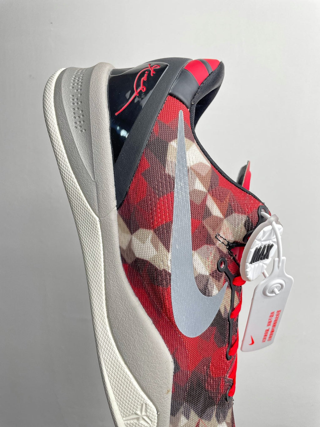 Basketball sneaker side view with red camo panels, large white swoosh, black collar.