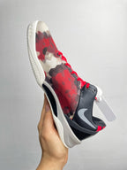 Basketball sneaker angled side view with red camo upper, dark swoosh, white sole.
