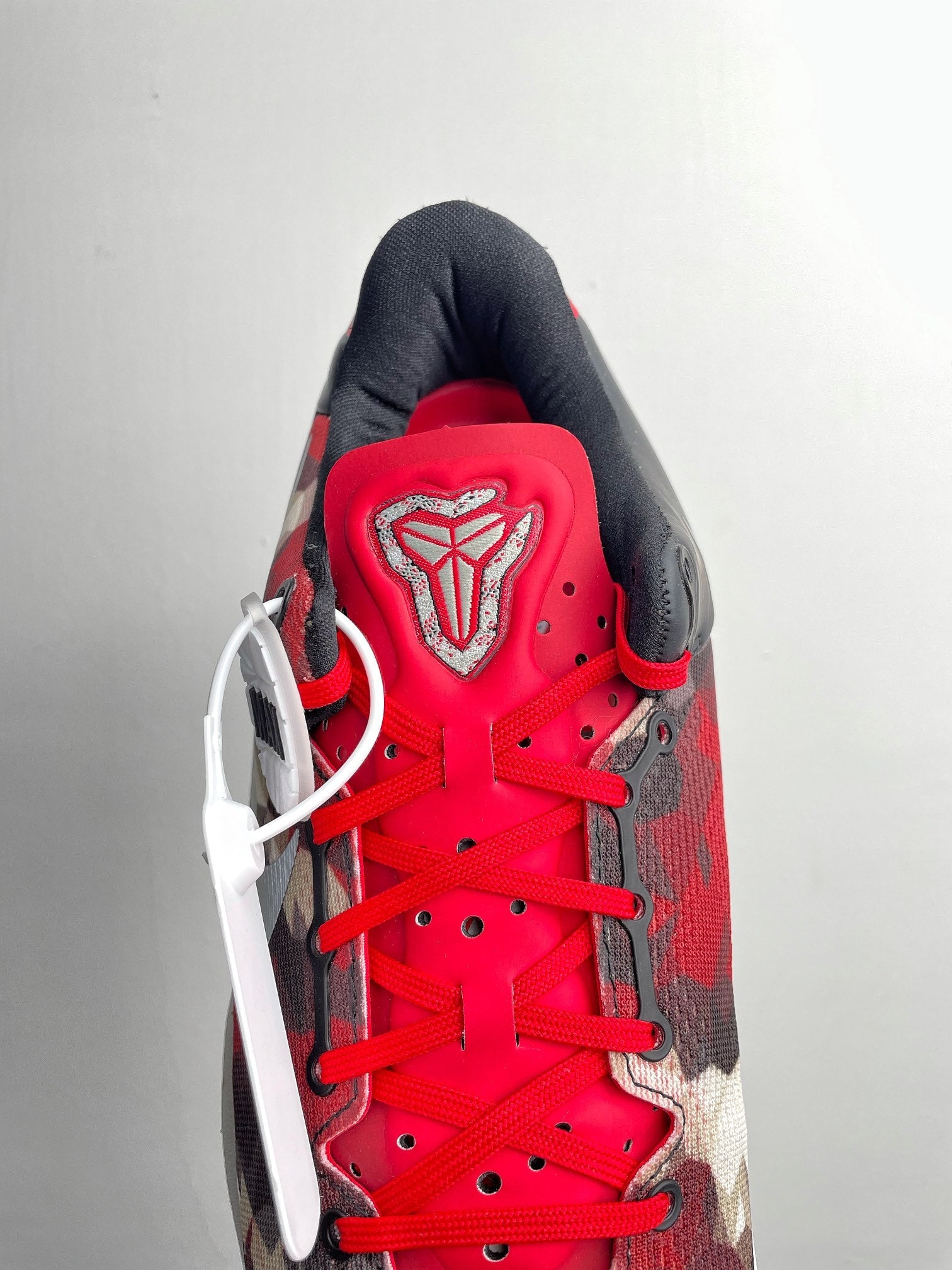 Basketball sneaker top view with bright red laces, red tongue, black heel lining.