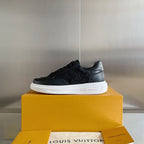 Black lace-up sneaker on yellow box with white sole and embossed logo pattern