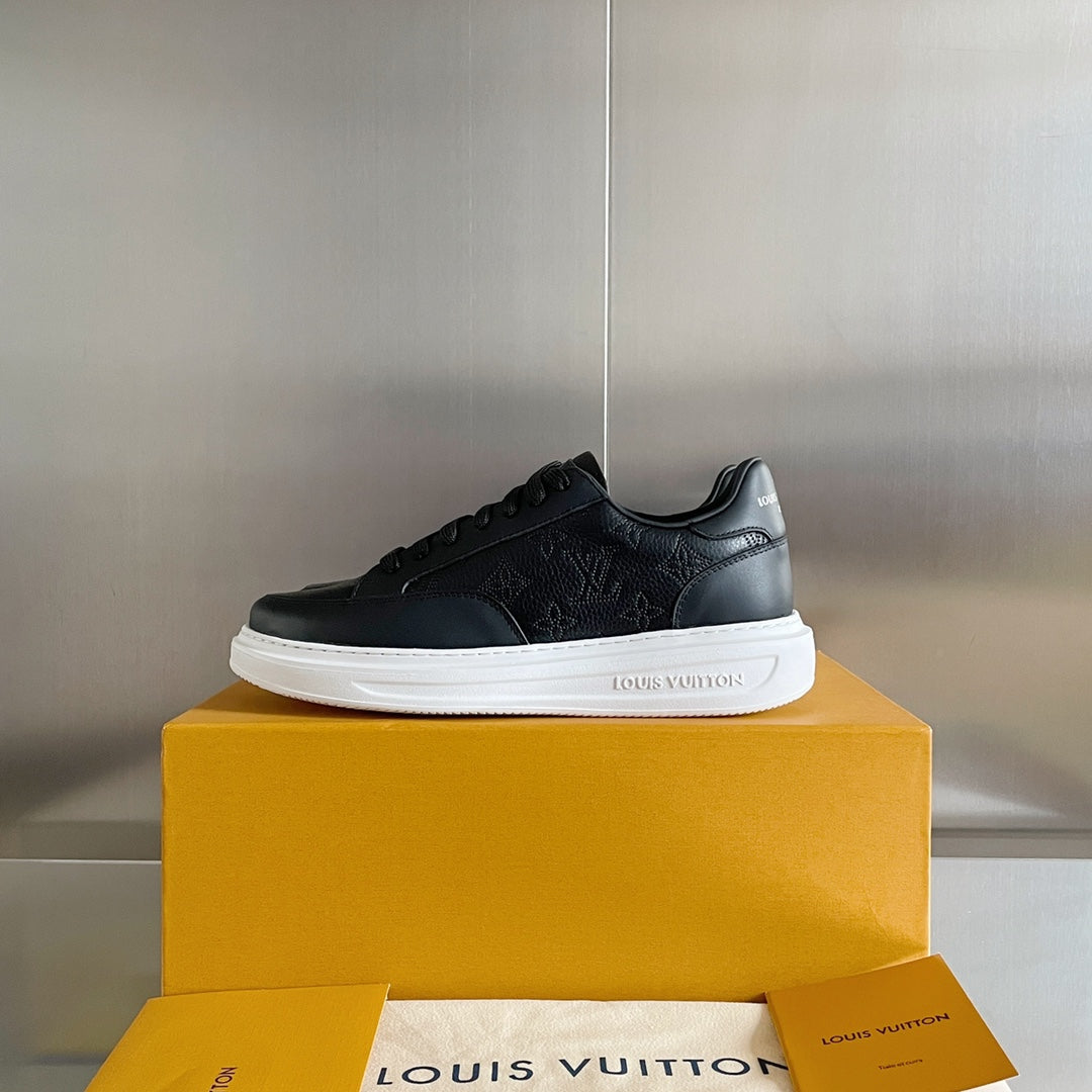 Black lace-up sneaker on yellow box with white sole and embossed logo pattern