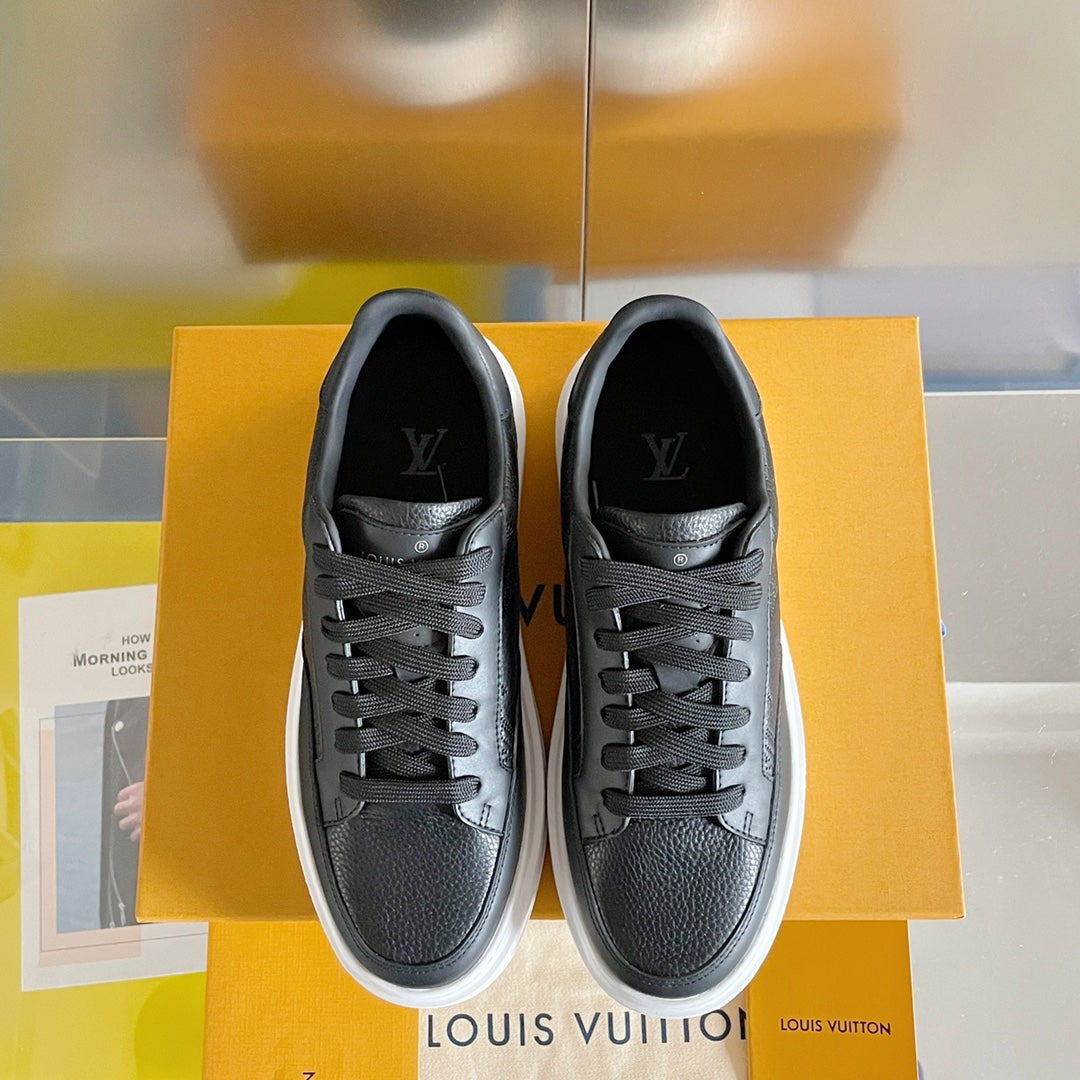 Black lace-up sneakers with white soles and logo at the tongue, pair on box