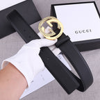 Black leather Gucci belt with gold-toned GG buckle, front view on papers
