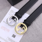 Two black leather Gucci belts with silver and gold-toned GG buckles on papers