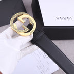 Black leather Gucci belt with gold-toned GG buckle, close-up on white tag