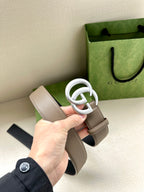 Two-tone leather belt with white-toned interlocking buckle on taupe strap; dark backing