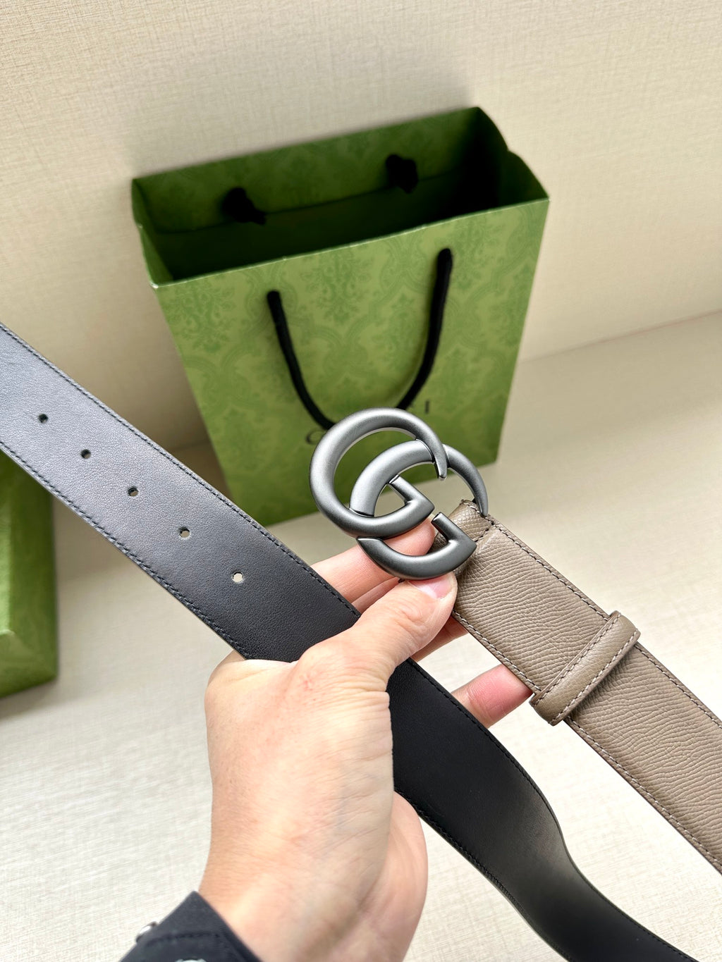 Two-tone leather belt with silver interlocking buckle; light strap with hole row