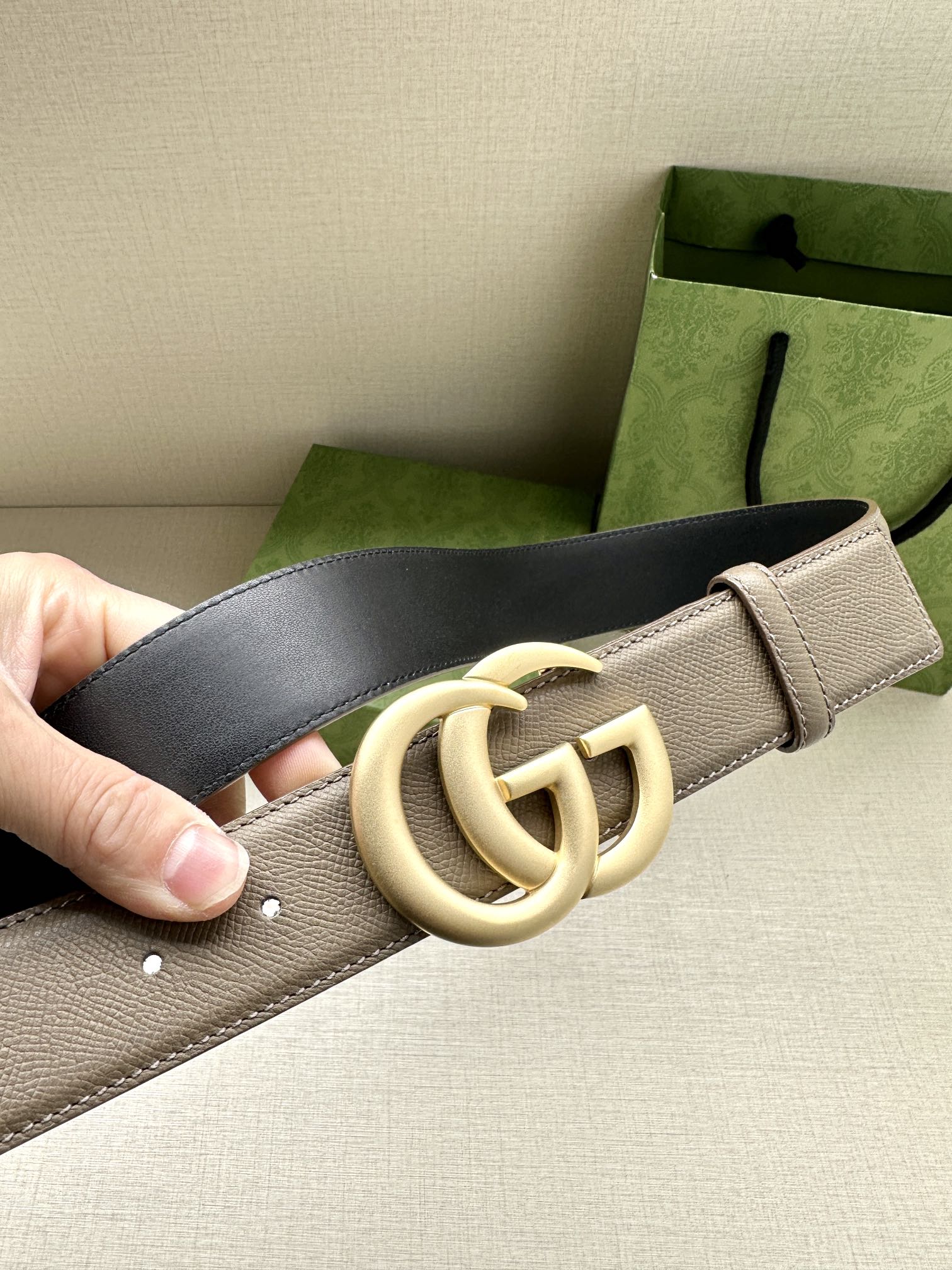 Two-tone leather belt detail: beige strap with gold-toned interlocking GG buckle