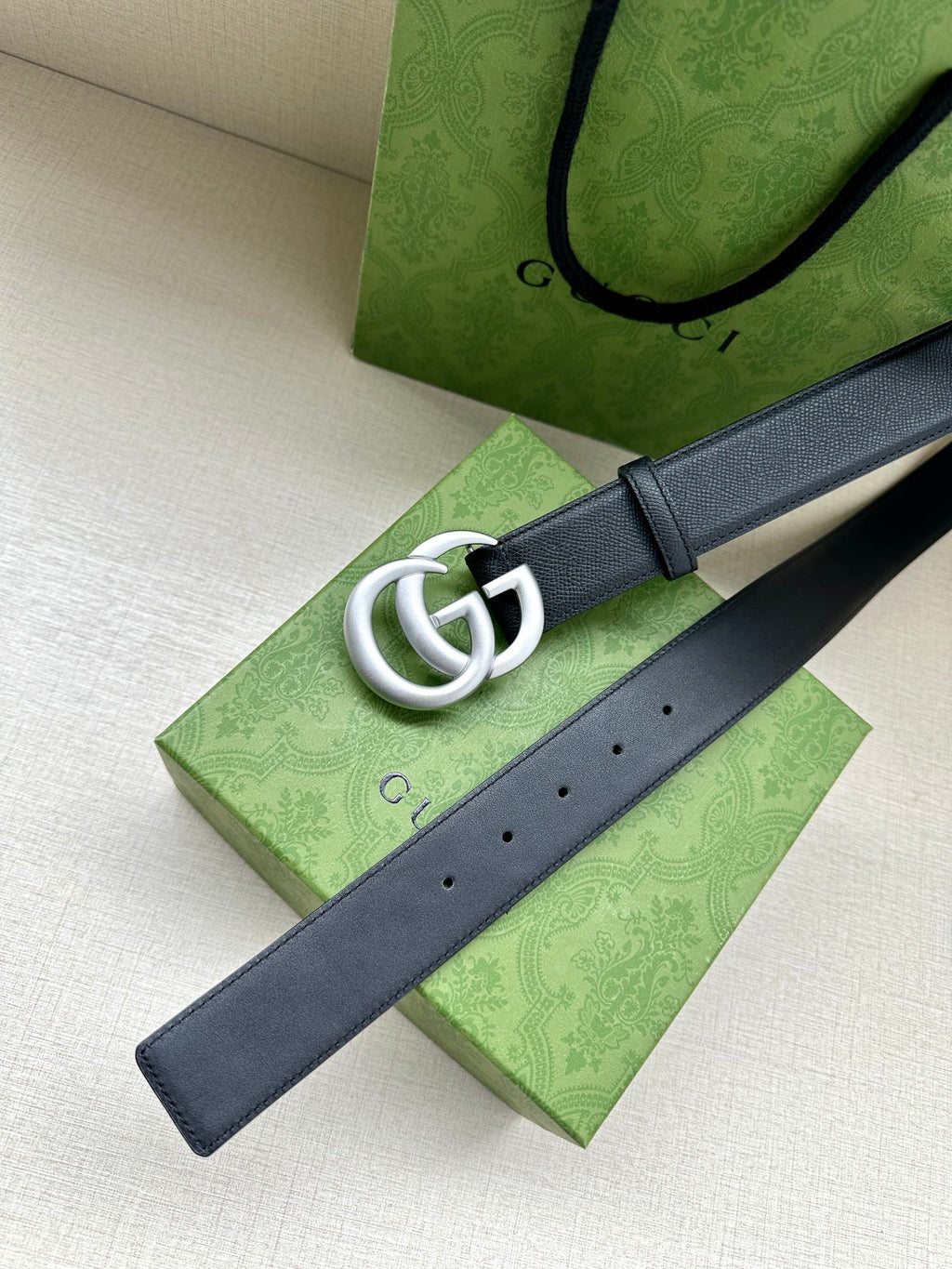 Navy leather belt with silver GG buckle on dark blue strap.