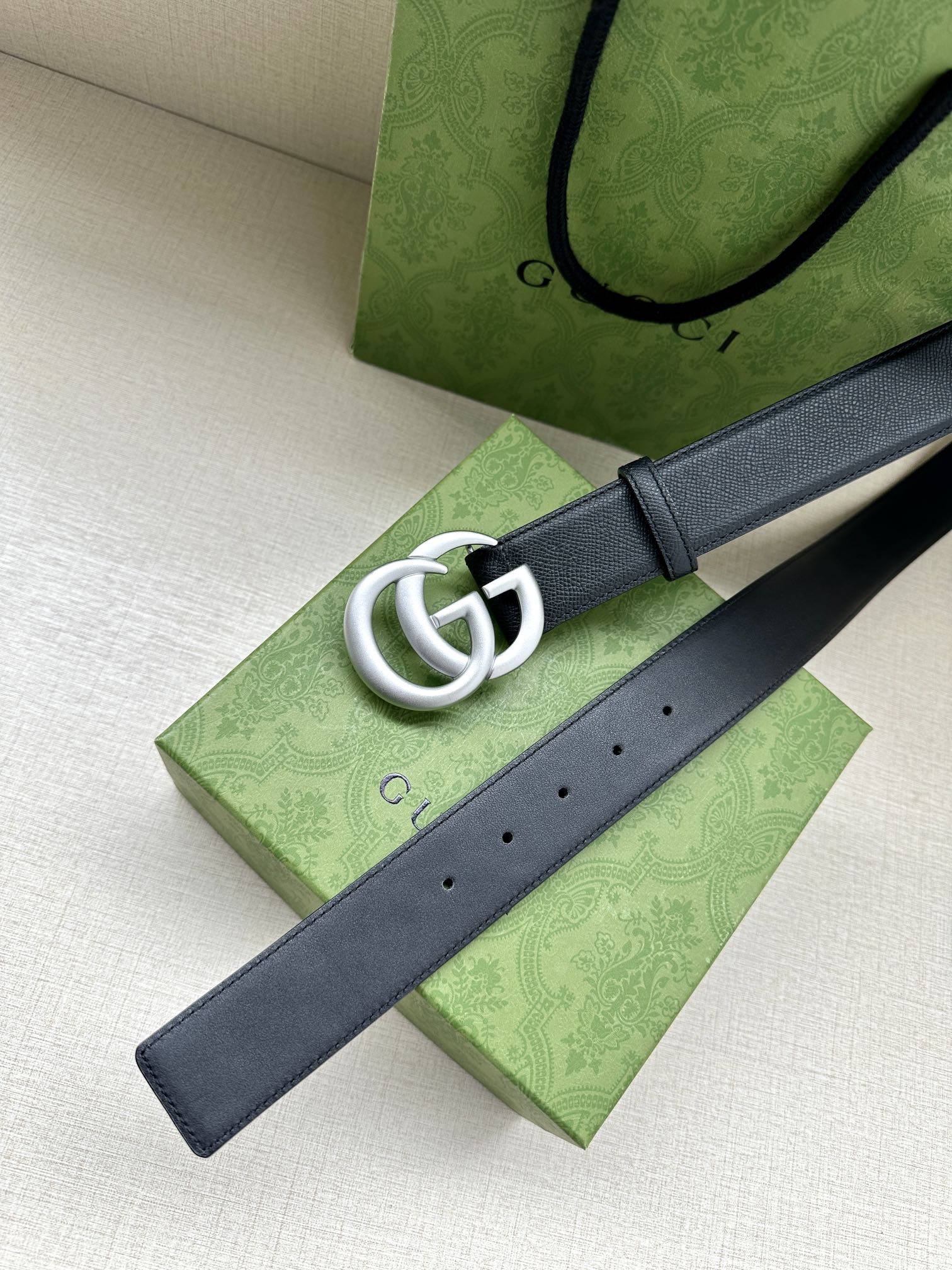 Navy leather belt with silver GG buckle on dark blue strap.