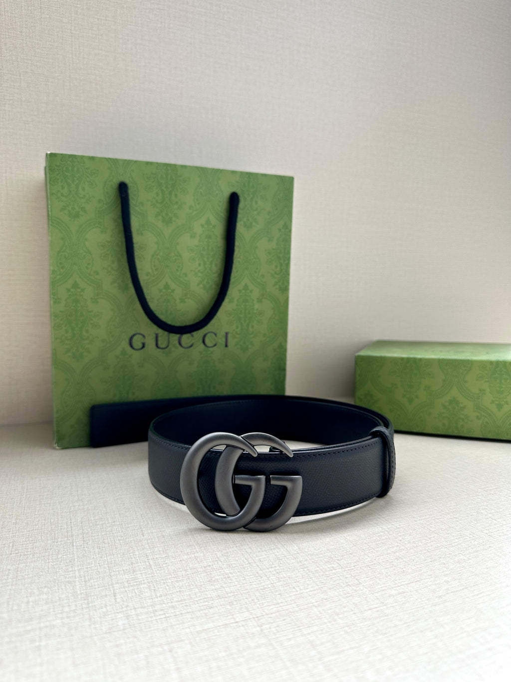 Navy leather belt with silver GG buckle, laid flat with punched holes.