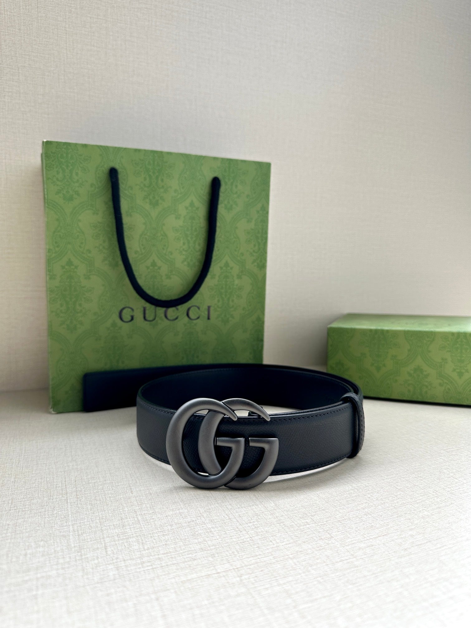 Navy leather belt with silver GG buckle, laid flat with punched holes.
