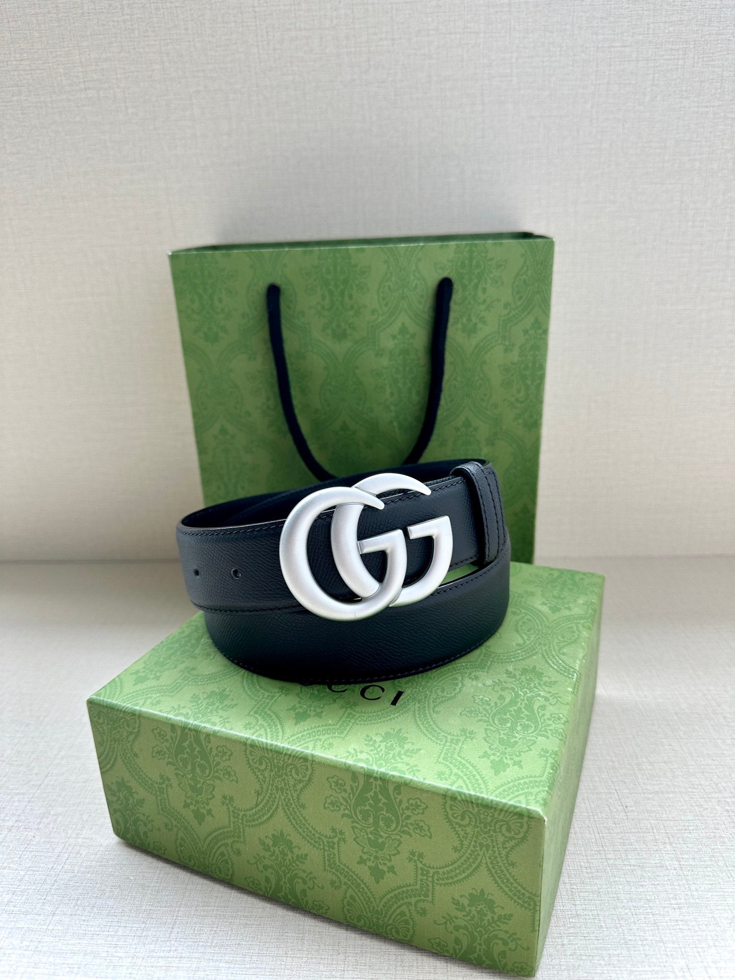 Navy leather belt with silver GG buckle, single strap with punched holes.