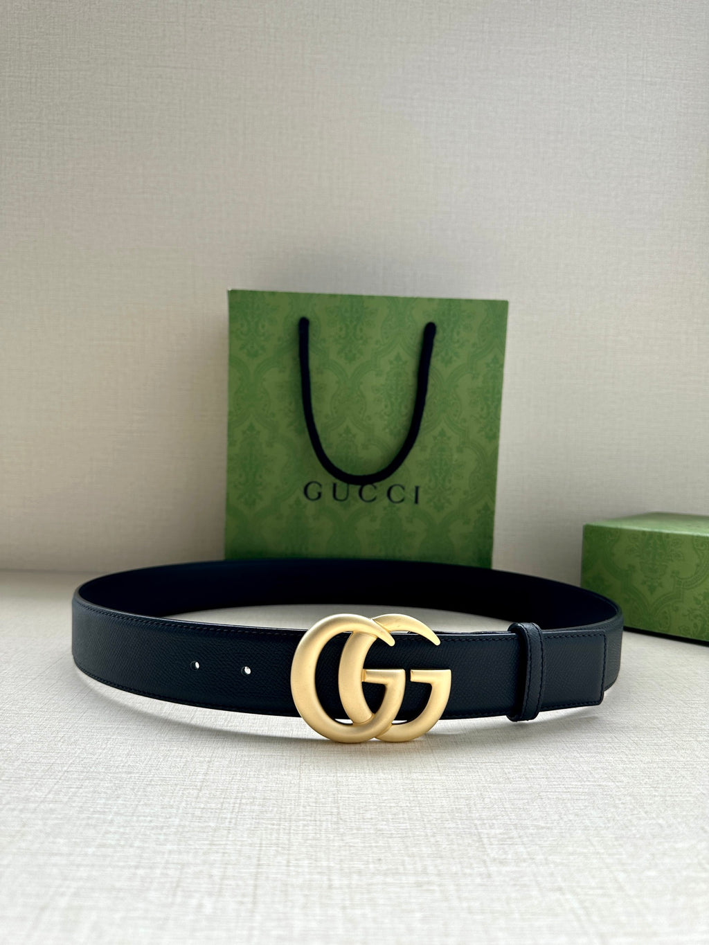 Dark blue leather belt with gold GG buckle, smooth strap with punched holes.