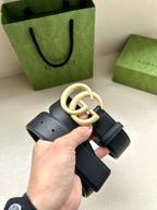 Dark blue leather belt with gold GG buckle and pin closure, belt end shown.