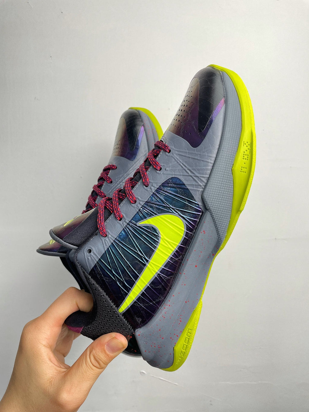 Basketball shoe shown from side: light gray upper with neon yellow sole and red laces