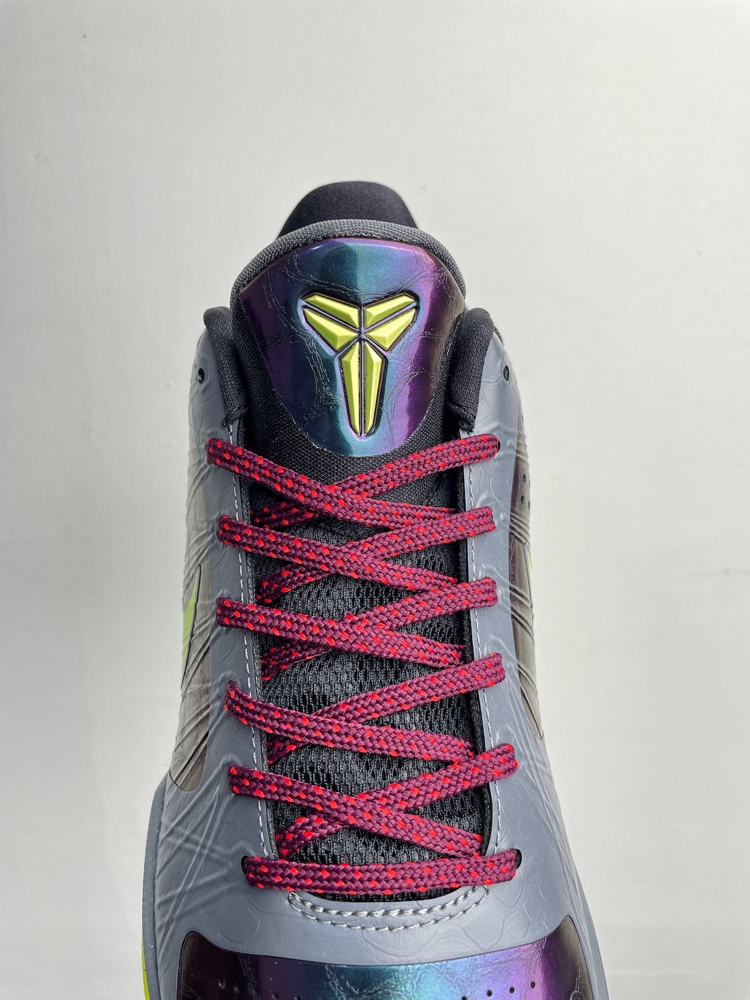 Basketball shoe back view with neon accents, gray upper, red laces, geometric heel logo