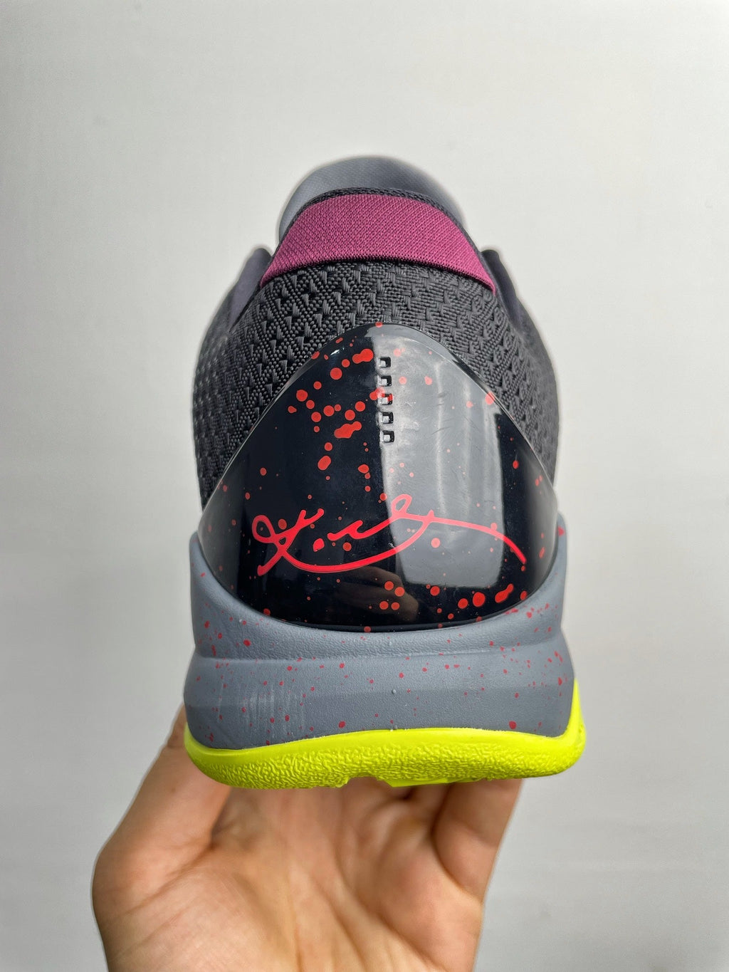 Basketball shoe back heel close-up in gray with purple collar, red graphic, neon yellow sole