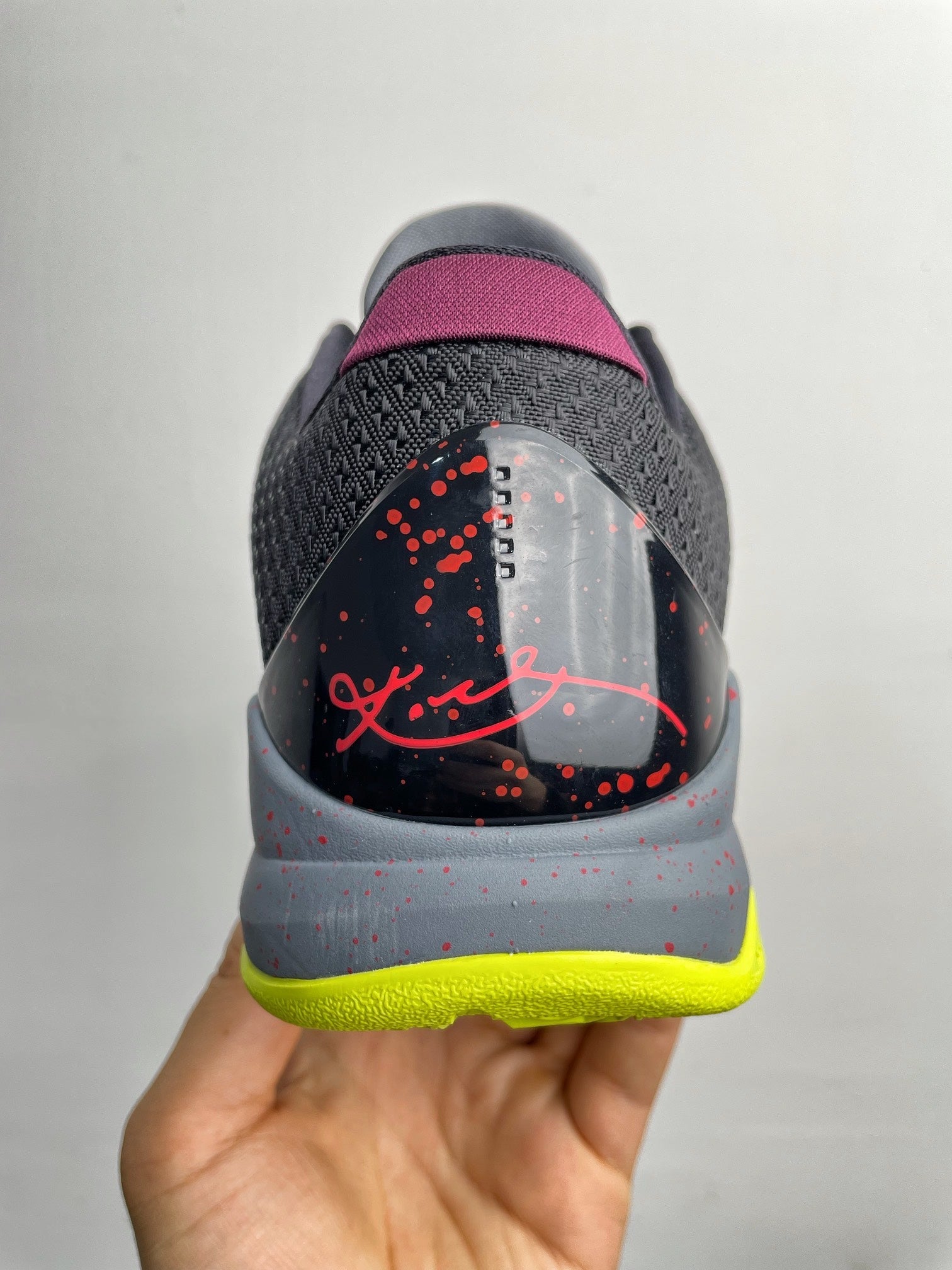 Basketball shoe back heel close-up in gray with purple collar, red graphic, neon yellow sole
