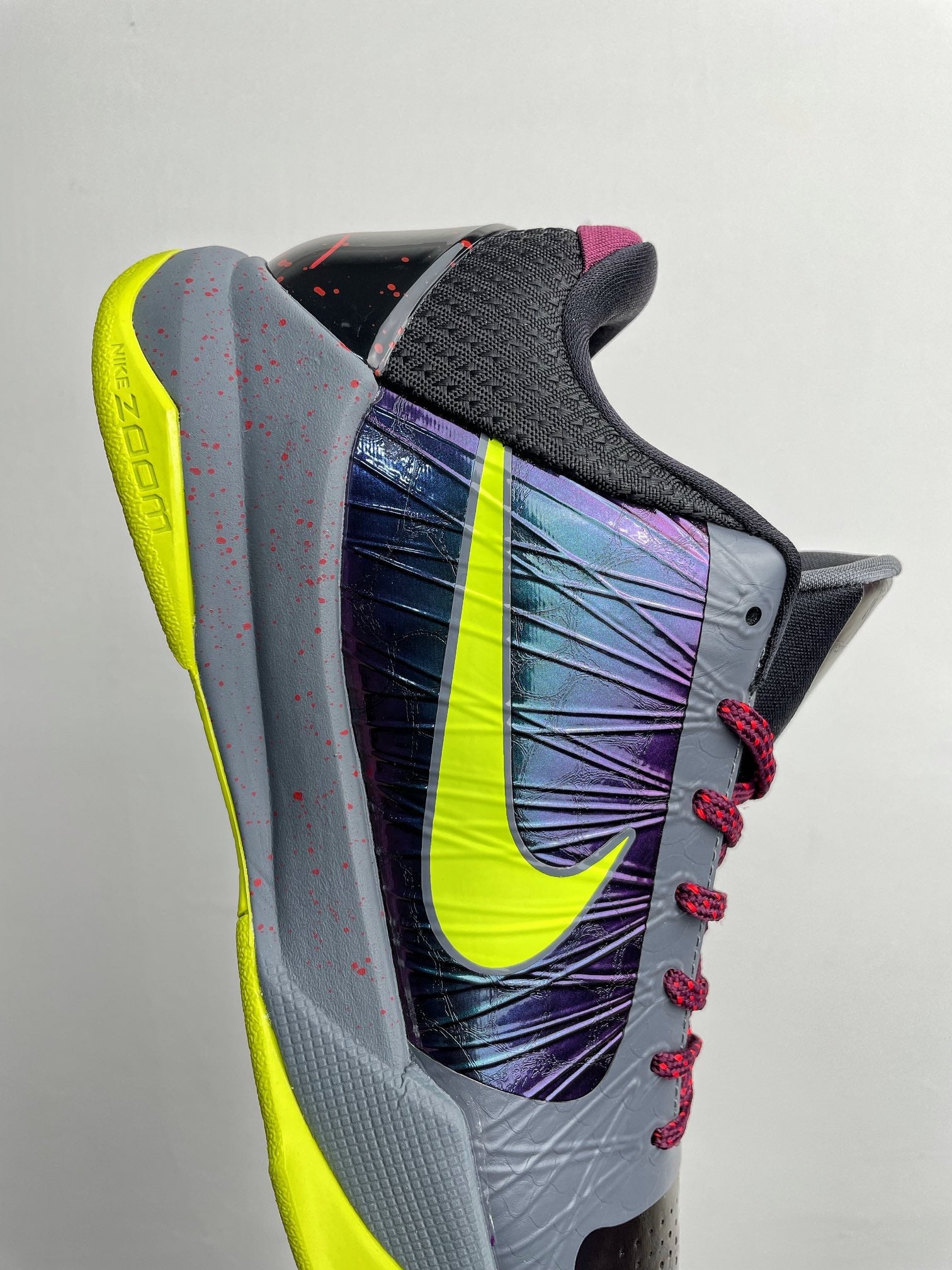 Basketball shoe heel and side view with neon yellow sole, purple graphic, red laces