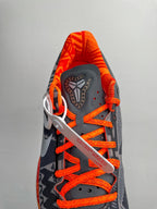 Basketball shoes with dark upper, orange laces, white logo patch