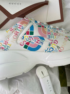 Gucci unisex sneaker upper close-up, multicolor logo print with gold hardware