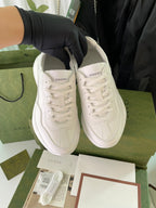 Pair of white Gucci lace-up sneakers displayed on green box