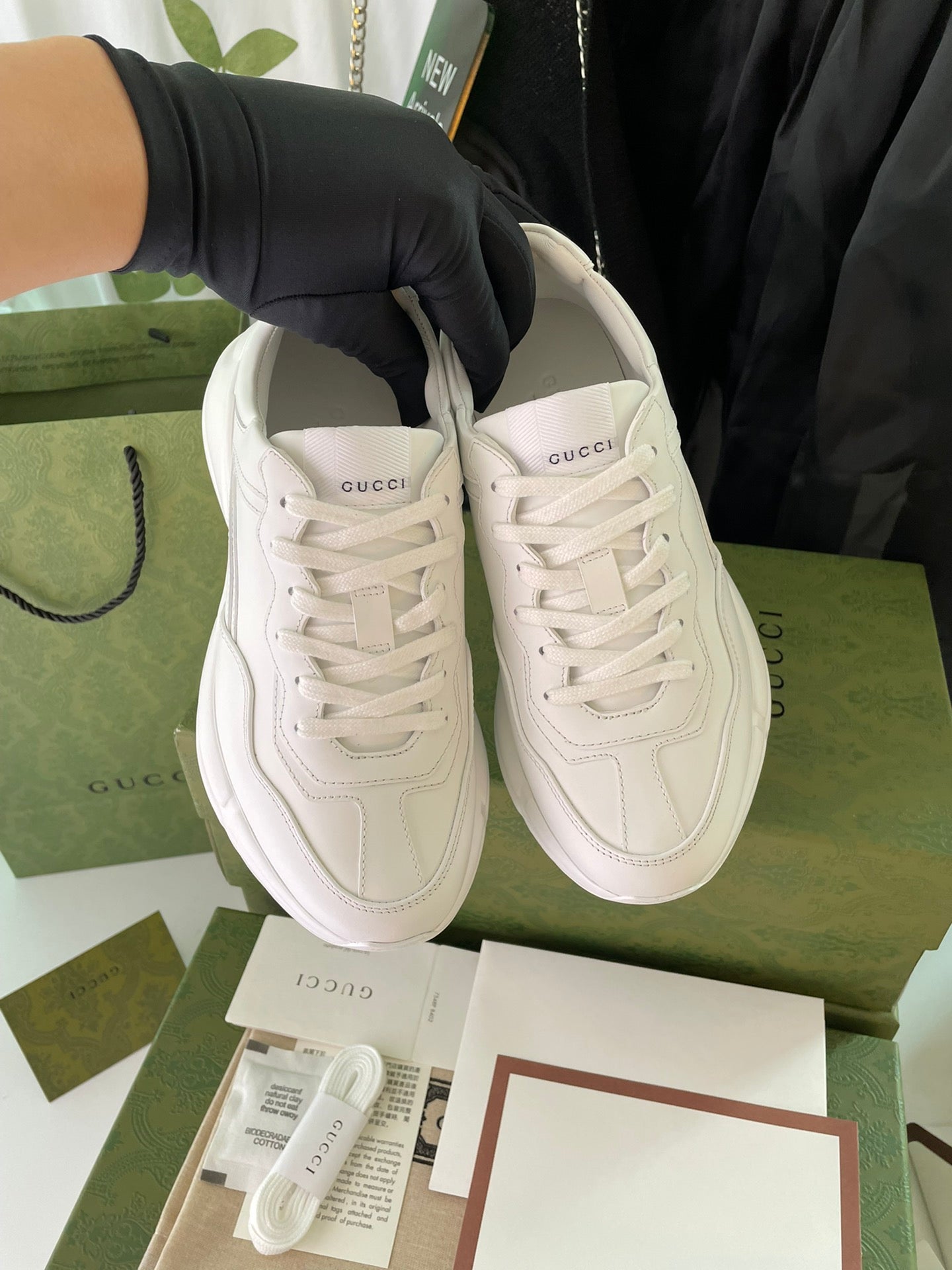 Pair of white Gucci lace-up sneakers displayed on green box