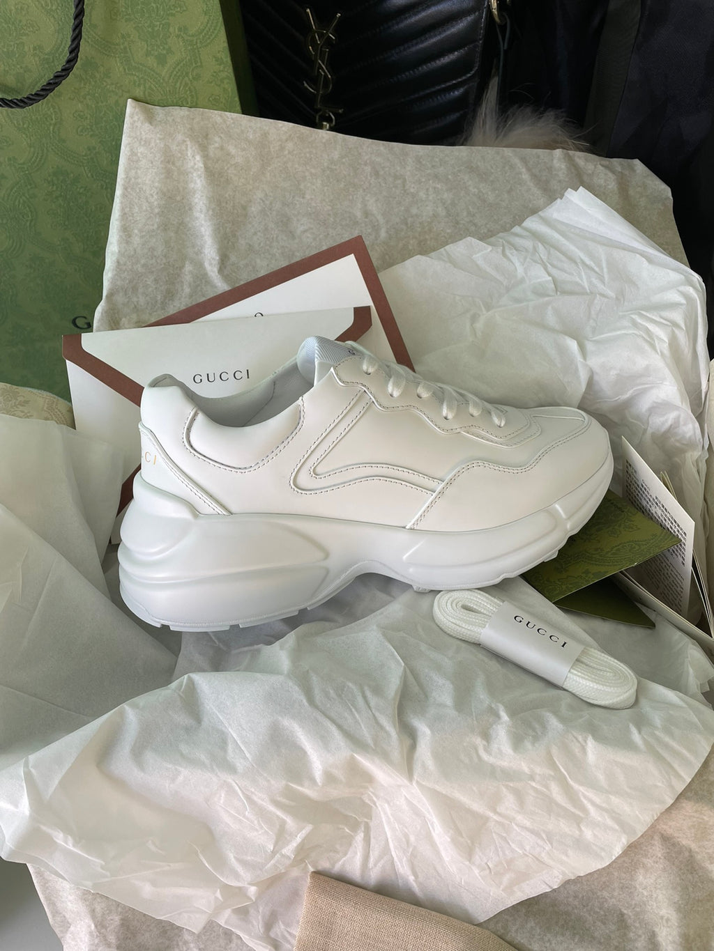White Gucci sneakers side view on tissue with shoebox and card