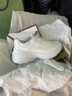 White Gucci sneakers side view on tissue with shoebox and card
