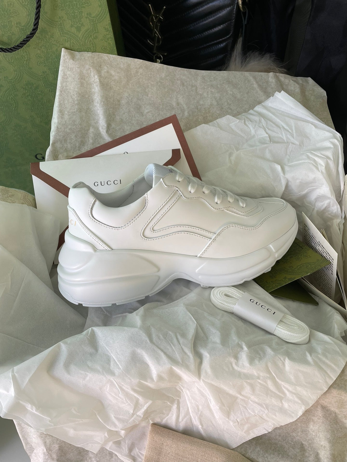 White Gucci sneakers side view on tissue with shoebox and card